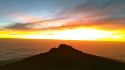 Sunrise and clouds over a small mountain.