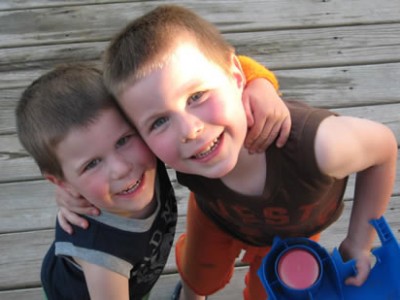 two young boys smiling with their arms around each others neck