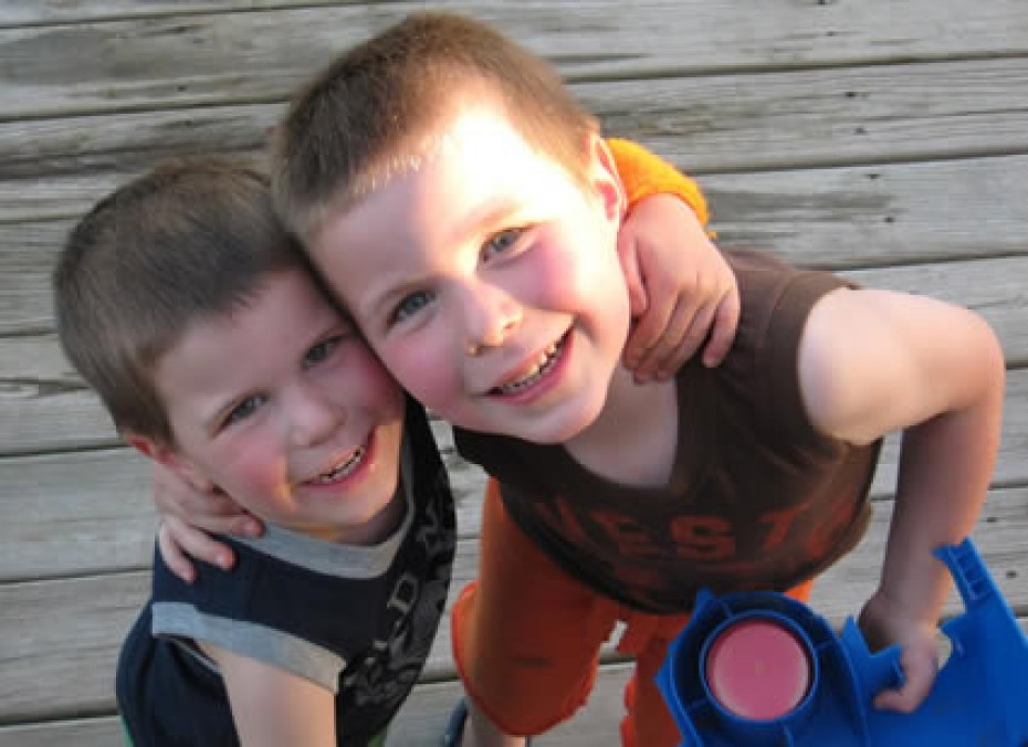 two young boys smiling with their arms around each others neck