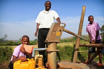 man and two children standing by a Living Water project
