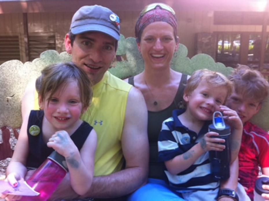 man and woman smiling and sitting with three children