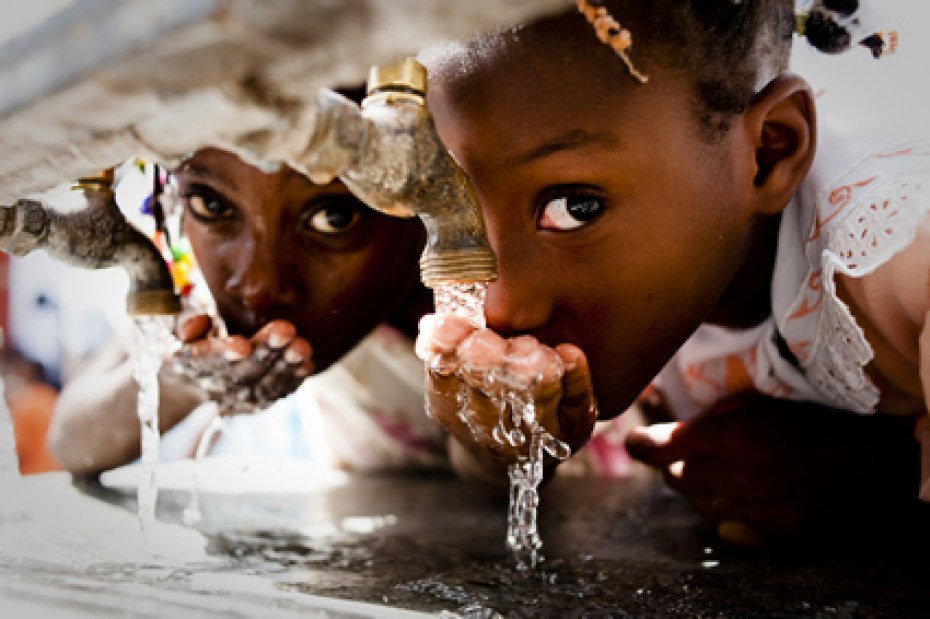 two girls drinking water from a faucet