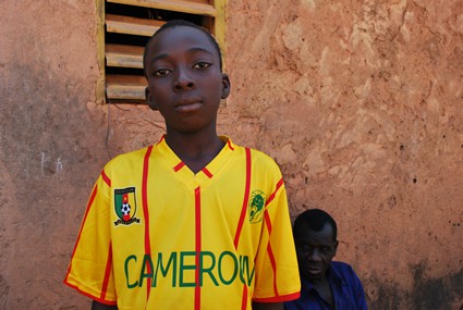 boy wearing yellow soccer jersey with another boy in the background
