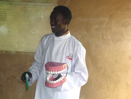 man in white smock holding a dental mockup