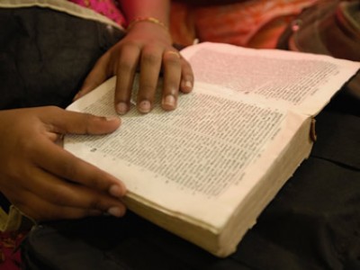 pair of hands on a well read open bible