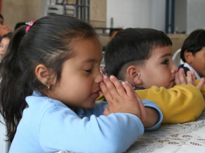 children sitting at table praying