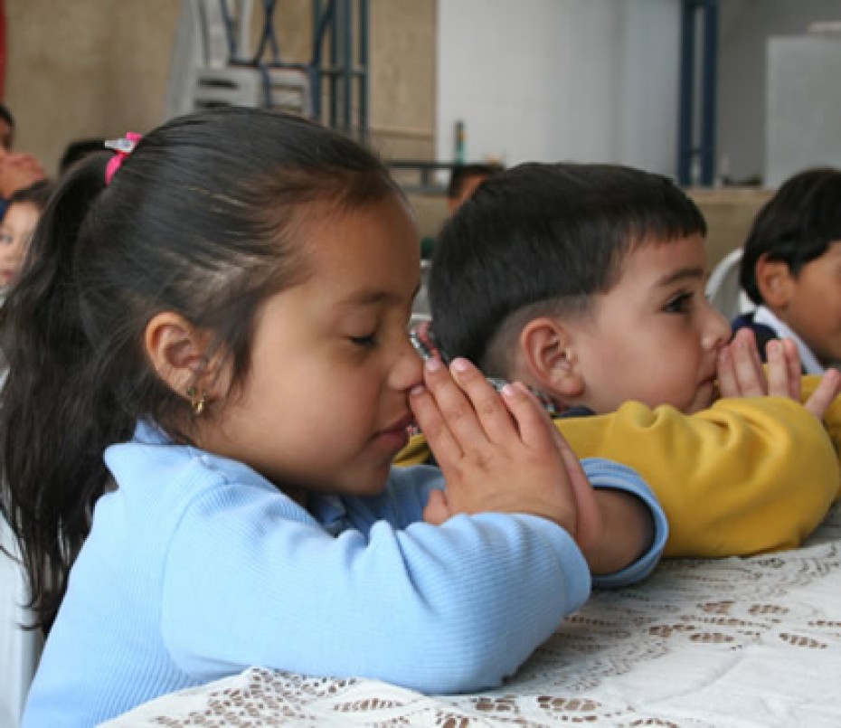 children sitting at table praying