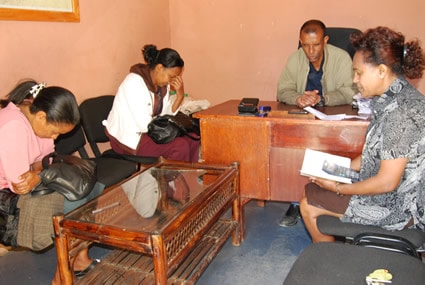 man sitting at desk with three women praying