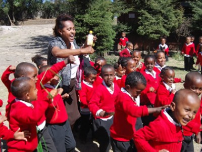 group of children wearing red sweaters outside with an adult