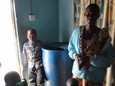 woman and child standing beside a blue barrel