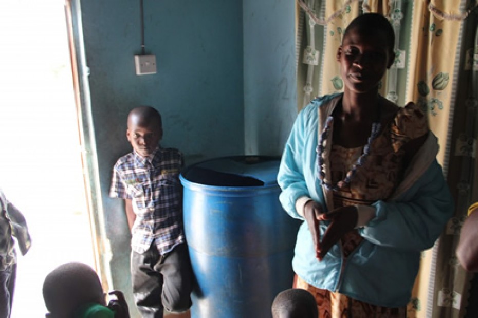 woman and child standing beside a blue barrel