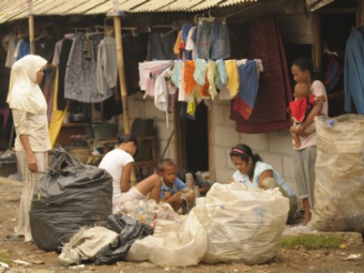 people outside house surrounded by filled garbage bags