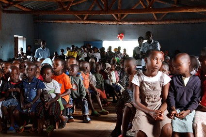 A group of children sitting on benches inside a building