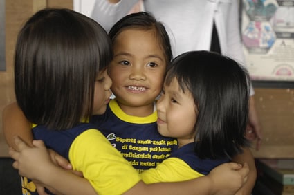 Three young smiling girls huddled together in a round hugging circle