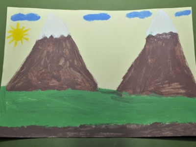 young childs drawing of green grass with two snow capped mountains