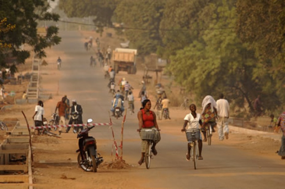 Many people riding bicycles on a rural road.