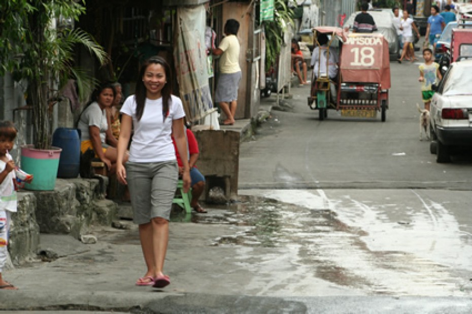 a smiling girl in a white shirt and gray shorts walking down a street