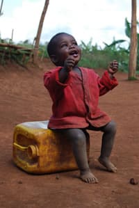 young child sitting on water container