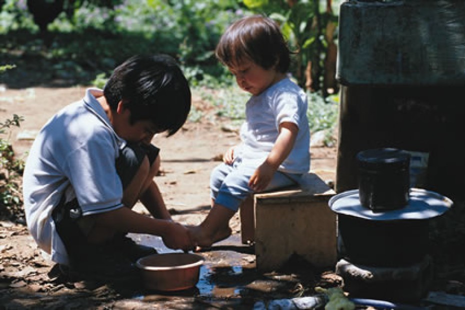 Young boy washing the feet of his little brother in Guatemala
