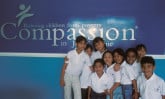 group of children in front of Compassion sign