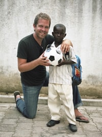 Man kneeling on one knee with a young boy holding a soccer ball