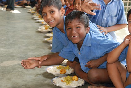 a group of children smiling as they prepare to eat