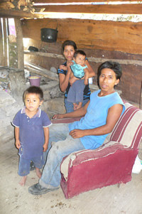 man sitting in chair with woman holding a baby standing next to him and a small boy