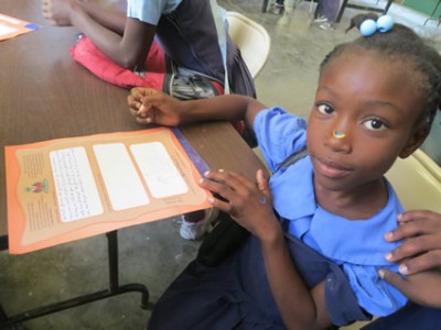 young girl sitting at a desk with a sticker on her nose