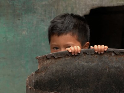 a little boy peeking over the edge of a metal barrel