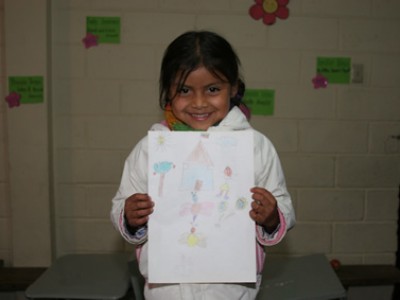 Young girl smiling holding a letter with a drawing