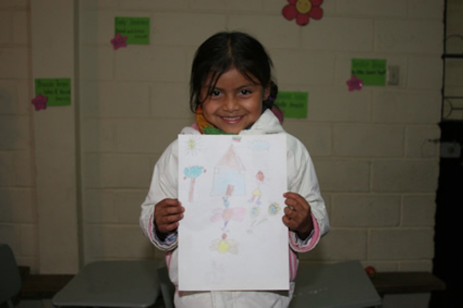 Young girl smiling holding a letter with a drawing
