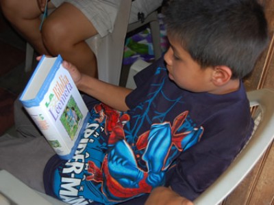 a boy wearing a spider man shirt holding a book