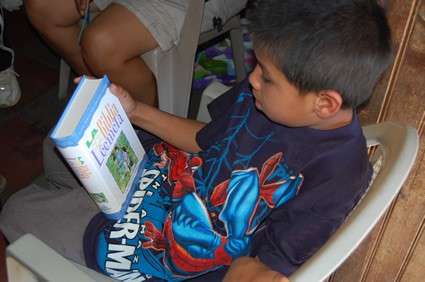 a boy wearing a spider man shirt holding a book
