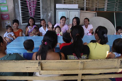 group of women and children sitting around a table and laughing