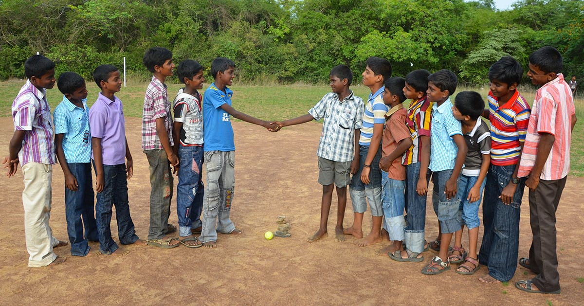 Two teams line up, shaking hands before playing the Seven Stones Game