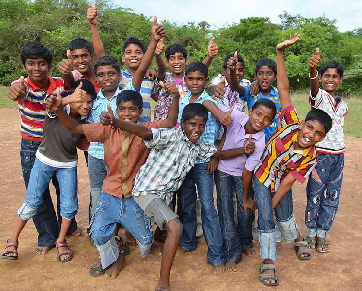 A group of boys in India give the thumbs up sign