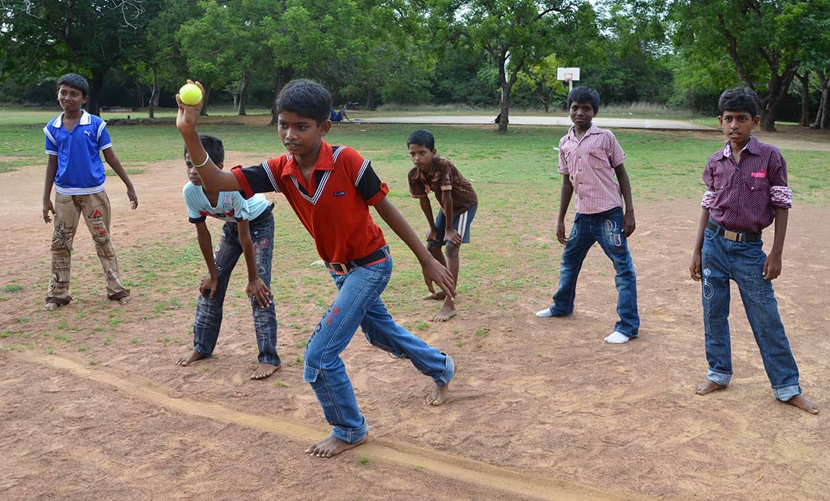 A boy throws a ball, with other boys standing behind him
