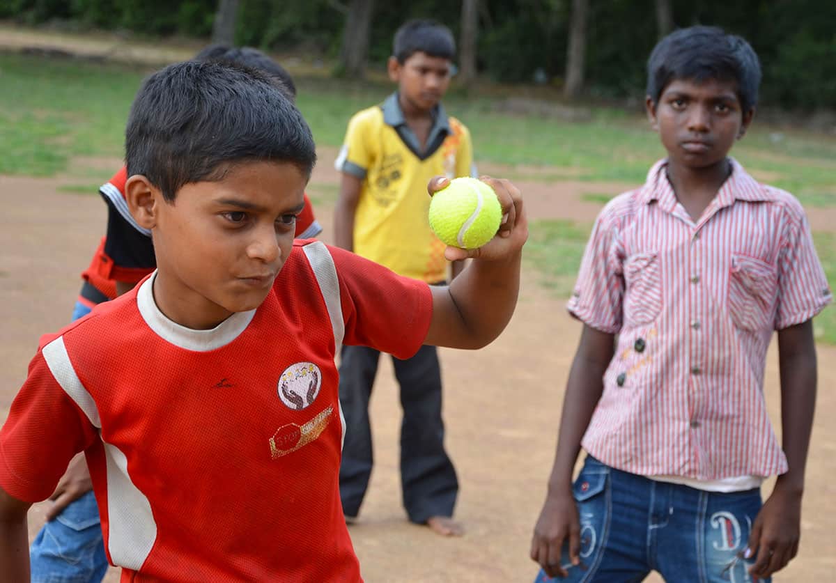 A boy in a red shirt prepares to throw a tennis ball
