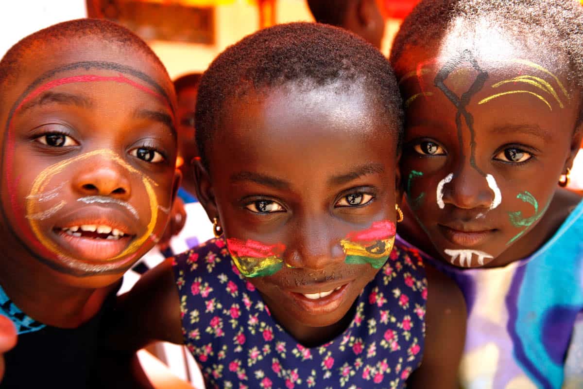 Ghanaian children stare curiously into the camera. Children have face paint, which is a Ghanaian tradition.