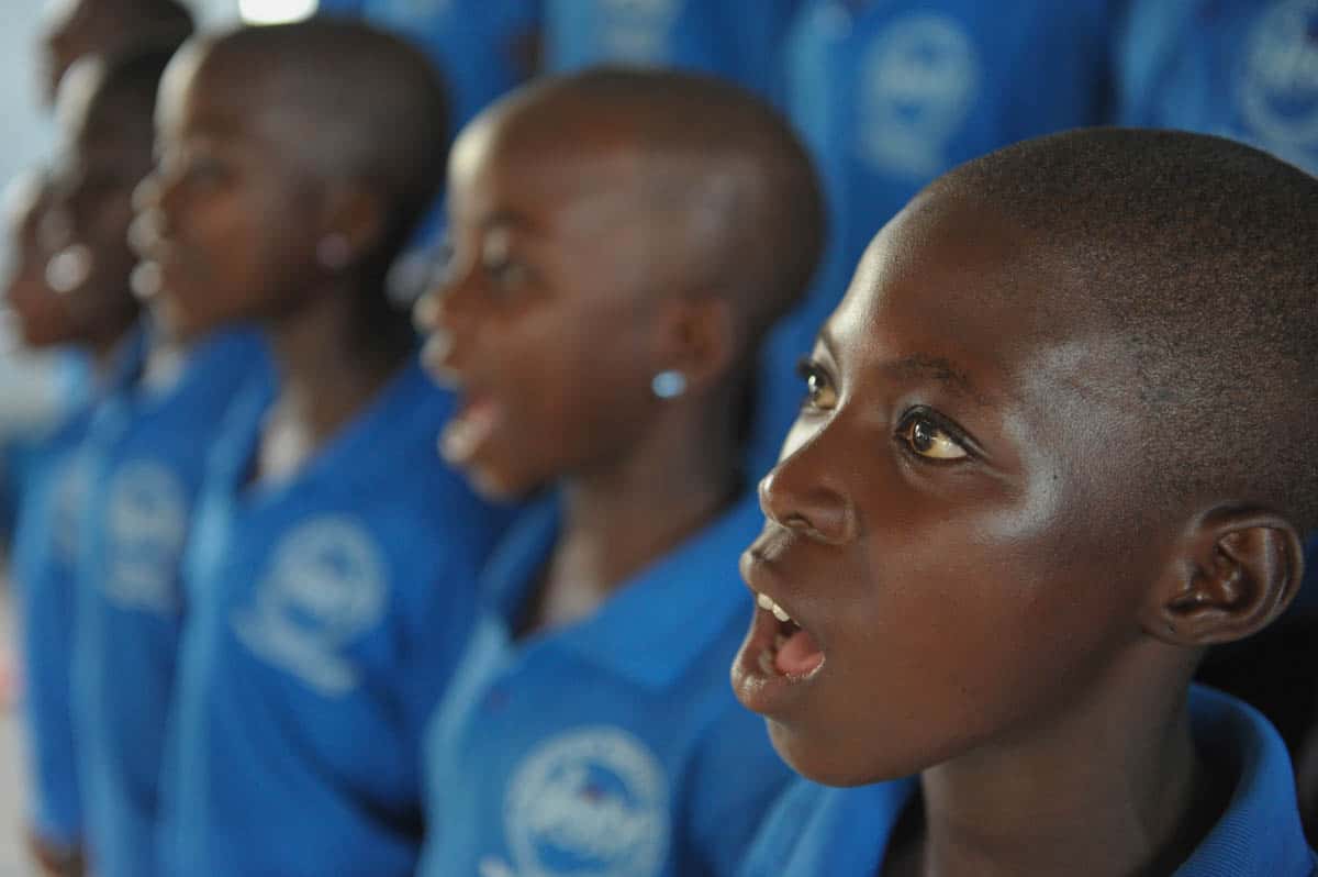 Children in Compassion's program sing. They are wearing matching blue shirts.