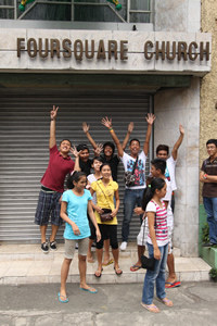group of teens outside a church with arms raised