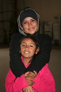 woman standing behind girl and hugging her neck