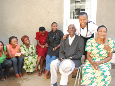 Family of 3 generations in Rwanda happily sitting around their parents outside their home