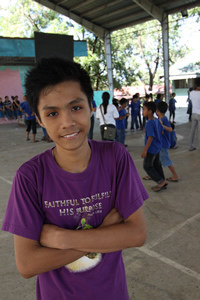 smiling boy with children playing in the background