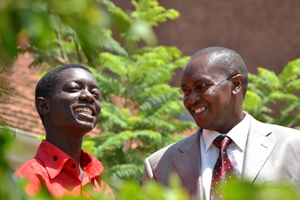 two smiling men surrounded by green bushes