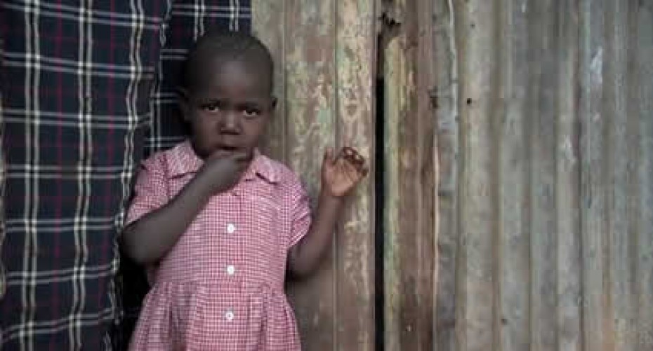 rescuing-the-future Small child standing outside by a wood building