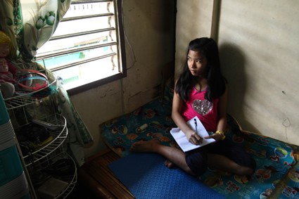 girl sitting on mat writing a letter