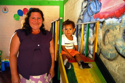 woman standing next to small child on a slide