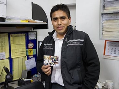 young man standing in an office holding a photograph