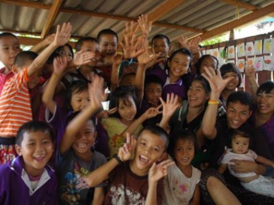 group of smiling happy children posing for the camera with raised hands and peace signs